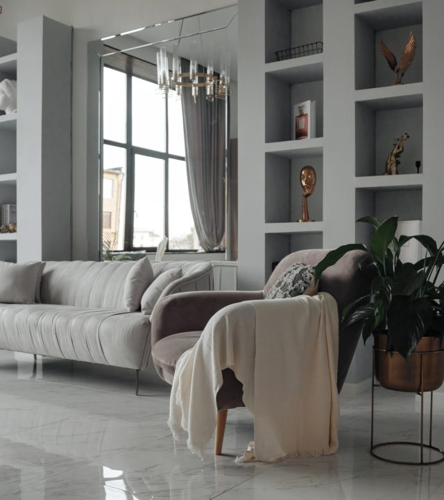 Modern interior of home living room with designer furniture with sofa, mirror, shelves, armchair and elegant personal accessories. Stylish neutral home decor. Design style concept. Copy ad text space